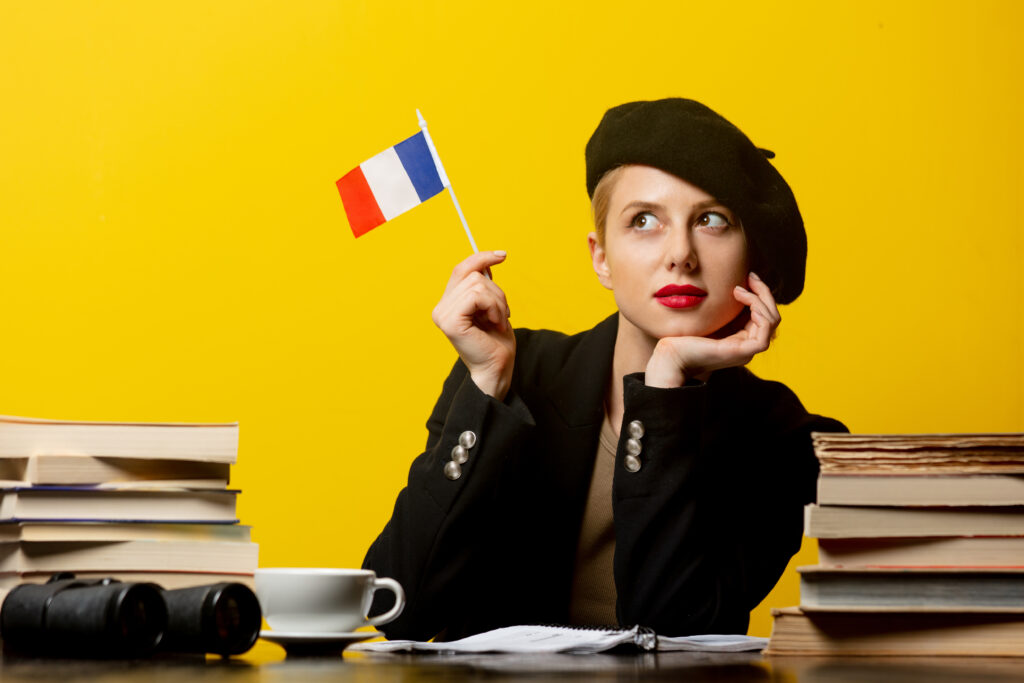 Style blonde woman in beret with French flag and books around on